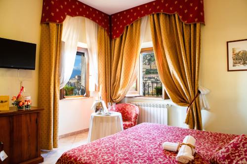 Hotel Il Cavalier D'Arpino في Arpino: غرفة نوم بسرير احمر وكرسي ونوافذ