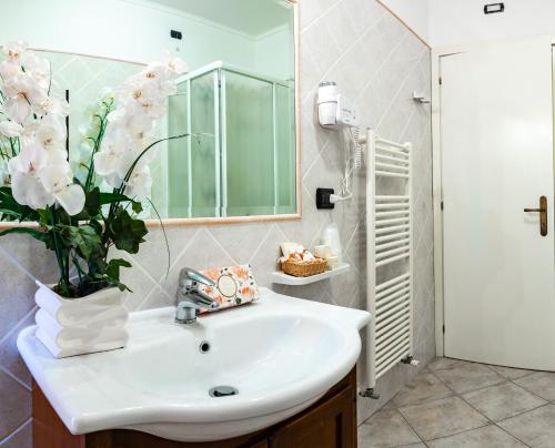 baño con lavabo y jarrón de flores en Hotel Il Cavalier D'Arpino en Arpino