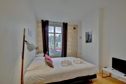 una camera con un letto bianco e una finestra di Les Halles et Hauteurs by Cocoonr a Bordeaux