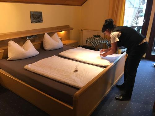 a woman making a bed in a hotel room at Hotel Hoxter Am Jakobsweg in Höxter