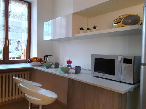 una cucina con bancone, forno a microonde e 2 sedie di Casa Genny a Garda