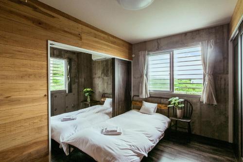 two beds in a room with wooden walls and windows at "NICE!" Ocean view of Ishigaki island, Okinawa/ Four-bedroom Villa in Ishigaki Island