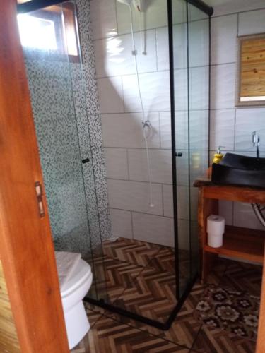 a bathroom with a shower and a toilet and a sink at Chalés Alvorada in Praia Grande