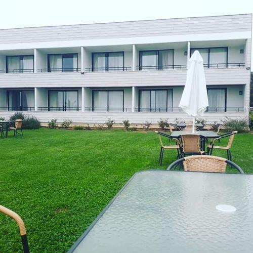 a table with an umbrella and chairs in front of a building at Hotel Del Valle Quilimari in Pichidangui