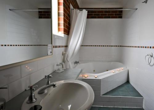 uma casa de banho branca com um lavatório e uma banheira em Poachers Paradise em Rutherglen