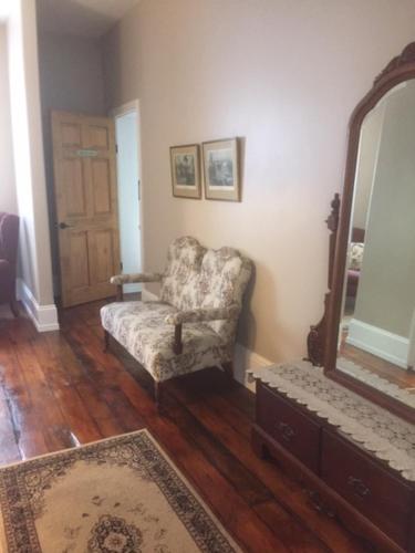 a living room with a chair and a mirror at Sir Isaac Brock B&B Luxury Suites in Brockville