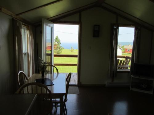 a dining room with a table and a view of the ocean at Chalets Nature Océan in Perce