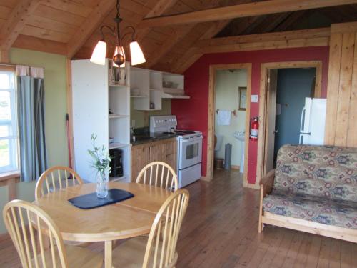 a kitchen and dining room with a table and a couch at Chalets Nature Océan in Perce