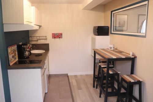 - une petite cuisine avec un comptoir et une table dans l'établissement Villa des sables avec 1 studio pour 2 personnes pouvant être complété par une chambre avec sa salle de bain et WC si 4 personnes, à Cabourg