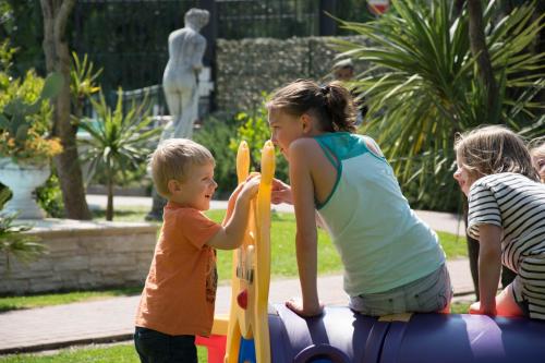 a woman and two children playing on a playground at Residenza Le Due Torri in Riva del Garda
