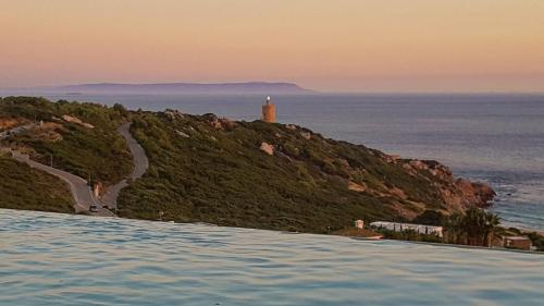 a swimming pool with a lighthouse in the ocean at Villa Alkaram de lujo con vistas panorámicas al mar in Zahara de los Atunes