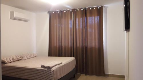 um pequeno quarto com uma cama e uma cortina castanha em Coronado Beach Paradise em El Llano del Medio