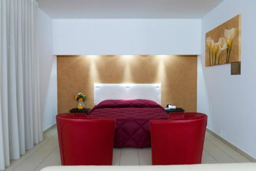 una camera con un letto rosso e due sedie rosse di Hotel 660 a Bisignano