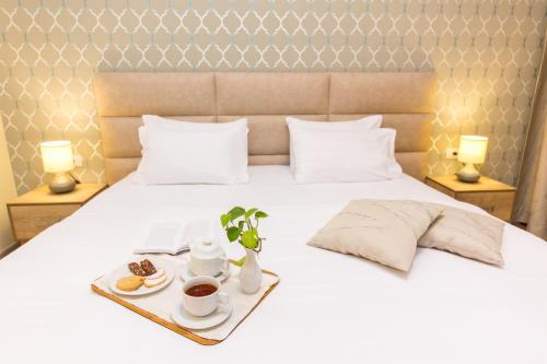 Una cama blanca con una bandeja de comida. en Hotel Baron, en Tirana