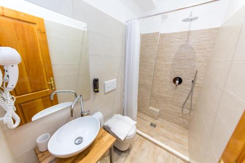 a bathroom with a toilet and a sink and a shower at Hotel Baron in Tirana