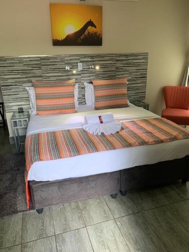 a large bed in a room with a red chair at Ecolux Boutique Hotel in Komatipoort