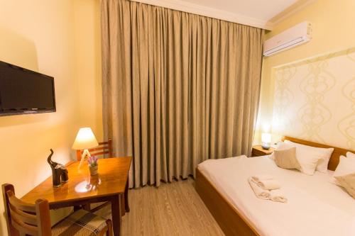 a hotel room with a bed and a desk and a television at Hotel Baron in Tirana