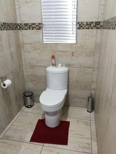a bathroom with a white toilet with a red rug at Kalahari Rus in Upington