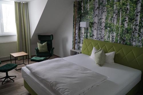 a bedroom with a white bed with a green headboard at Hotel Garni in Westerheim