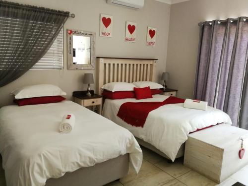 2 camas en un dormitorio con corazones en la pared en Kalahari Rus, en Upington