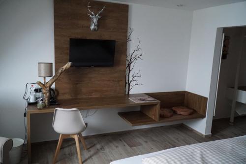 a bedroom with a desk with a television on a wall at Hotel Garni in Westerheim