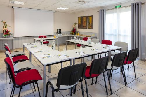 a conference room with tables and chairs and a whiteboard at The Originals City, Hôtel Le Pavillon, Béziers Est in Béziers