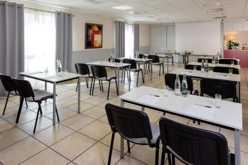 a dining room with tables and chairs and a room with windows at The Originals City, Hôtel Le Pavillon, Béziers Est in Béziers