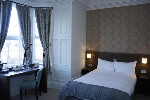 a hotel room with a bed and a desk and window at Corriegarth Hotel in Inverness