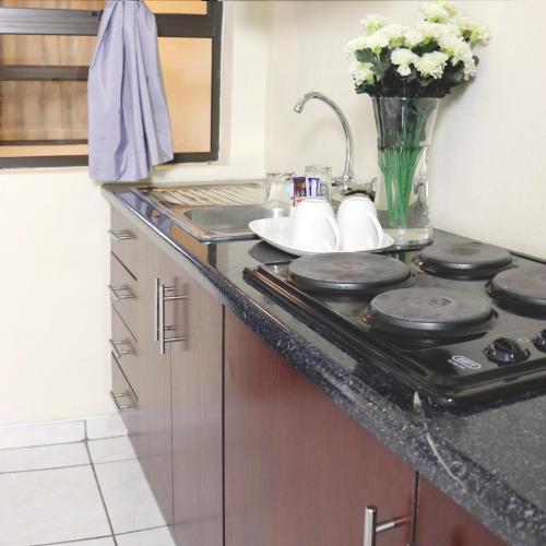 a kitchen counter with a stove and a vase of flowers at Tribute Guest House Matala in Maseru