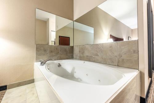 - białą wannę w łazience z dużym lustrem w obiekcie Red Lion Inn & Suites Mineral Wells w mieście Mineral Wells