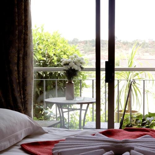 a bedroom with a bed and a table with a vase of flowers at Tribute Guest House Matala in Maseru
