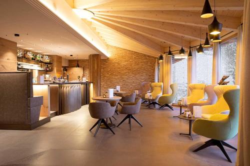 a restaurant with yellow chairs and tables and a bar at Hotel Nordik in Andalo