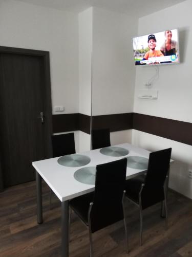 a white table with chairs and a tv on the wall at Apartmany Agatha in Loučná nad Desnou