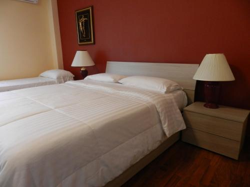 1 dormitorio con 1 cama blanca grande y 2 lámparas en B&B Joe, en Valguarnera Caropepe