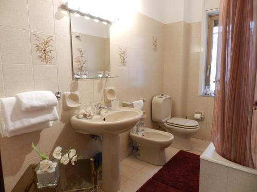 een badkamer met een wastafel, een toilet en een spiegel bij B&B Joe in Valguarnera Caropepe