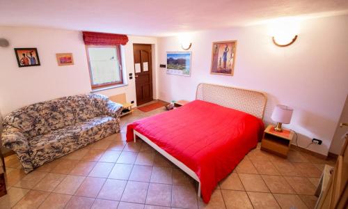 a bedroom with a red bed and a couch at B&B da Verena in Fenis
