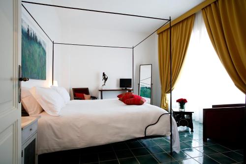 una camera da letto con un grande letto bianco con cuscini rossi di La Locanda Delle Donne Monache a Maratea