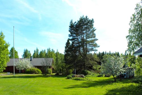 a yard with green grass and a house and trees at Hidden House Pirttijärvi in Jämsä