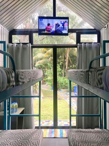 a room with two bunk beds with a tv and a window at Lanzones Cabana in Mambajao