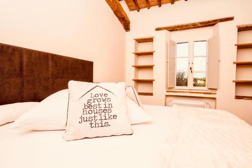 Una cama con una almohada que dice que el amor crece mejor en casas como esta en Locanda della Scala en San Quirico dʼOrcia