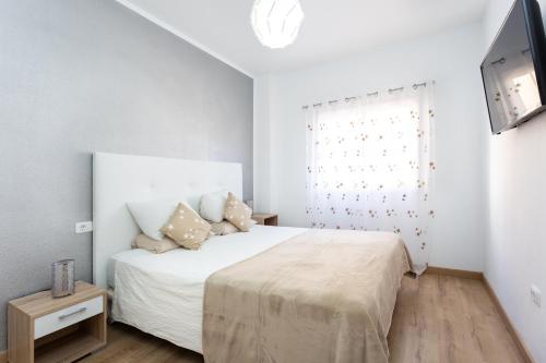 Habitación blanca con cama y TV en Home2Book Charming Caletillas Pool, en Candelaria