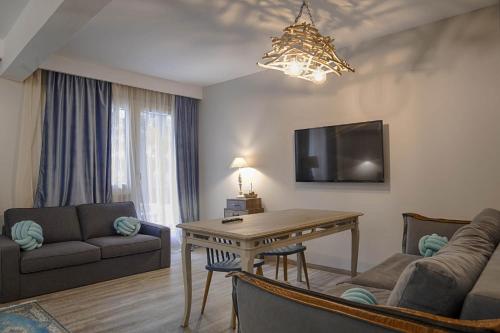 a living room with a table and a couch and a tv at Sali Boutique hotel in Alexandroupoli