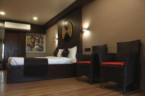 a hotel room with a bed and two chairs at Hotel Stellar in Vadodara