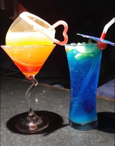 two cocktails sitting on a table next to a drink at Hotel Stellar in Vadodara