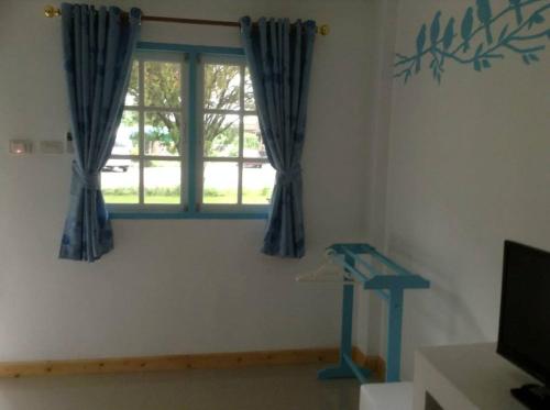 a living room with a window with blue curtains at Bamboo House Resort in Kanchanaburi City