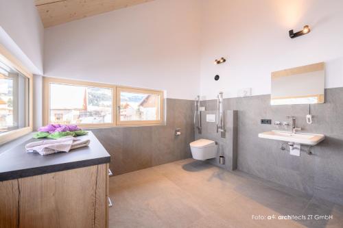 a bathroom with a sink and a toilet at Apart & Pension Wassermann inklusive Sommerbergbahnticket in Tannheim