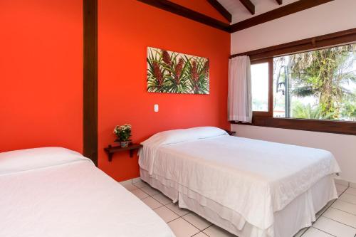 2 Betten in einem Zimmer mit orangefarbenen Wänden in der Unterkunft Pousada Peixes do Mar in Ubatuba