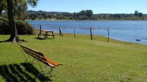 un banco del parque y una mesa de picnic junto a un lago en Cabañas Amanecer en el Lago en Villa del Dique