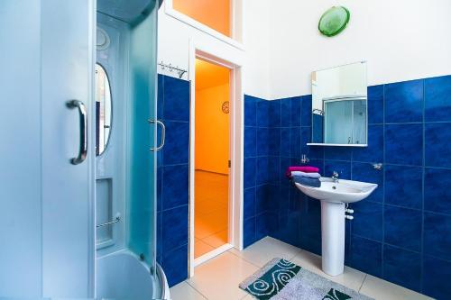y baño azul con lavabo y ducha. en Hostel Hunter House en Tomsk