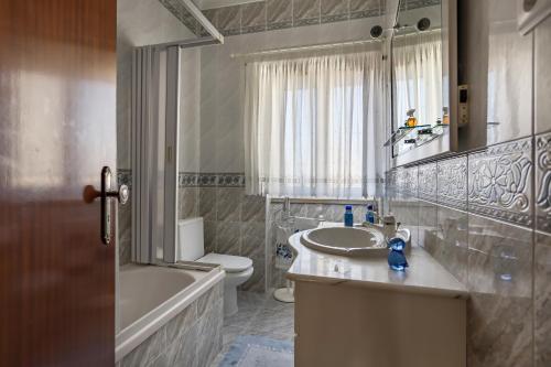 a bathroom with a sink and a tub and a toilet at Sea & Relax Villa Nazaré in Nazaré